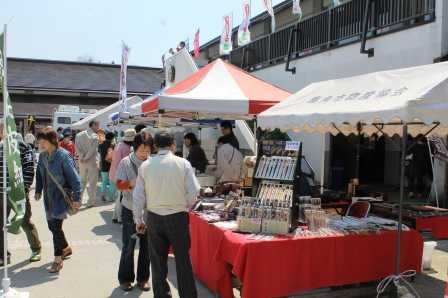 (写真)物産展にてお店のテントが立ち並び人々が立ち寄っている様子